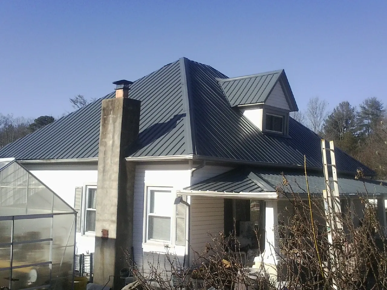 Dark blue standing seam metal roof on a white farmhouse with dormer — Slate & Tile Roof Repair by Roofing Brothers in Westfield